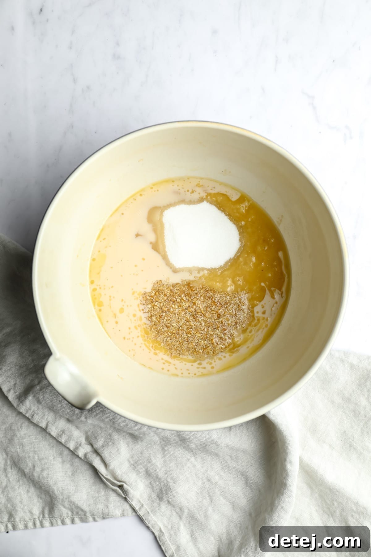 bowl with flaxseeds, sugar and milk/butter on white marble backdrop