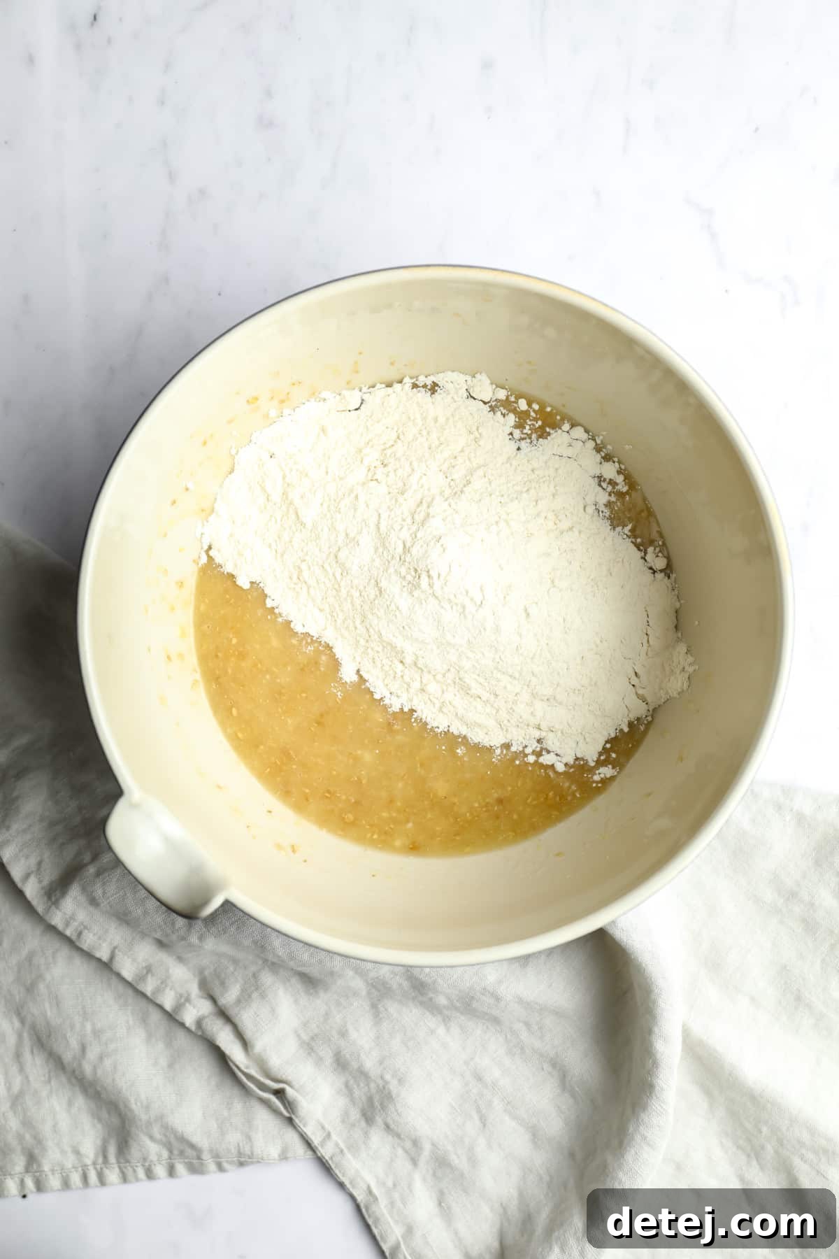 yellow mixture with flour on top in a bowl on white background