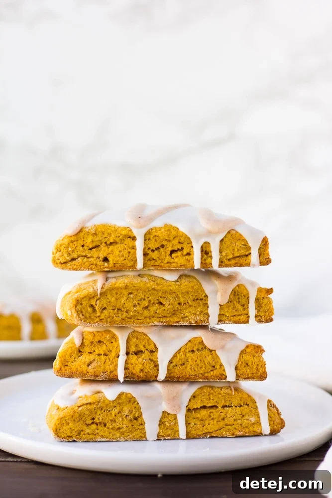 A stack of vegan pumpkin scones with white background, showing their soft texture and light glaze.