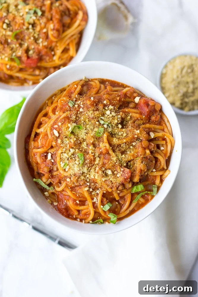 A close-up of Instant Pot Spaghetti in a white bowl, garnished with fresh basil, ready to eat.
