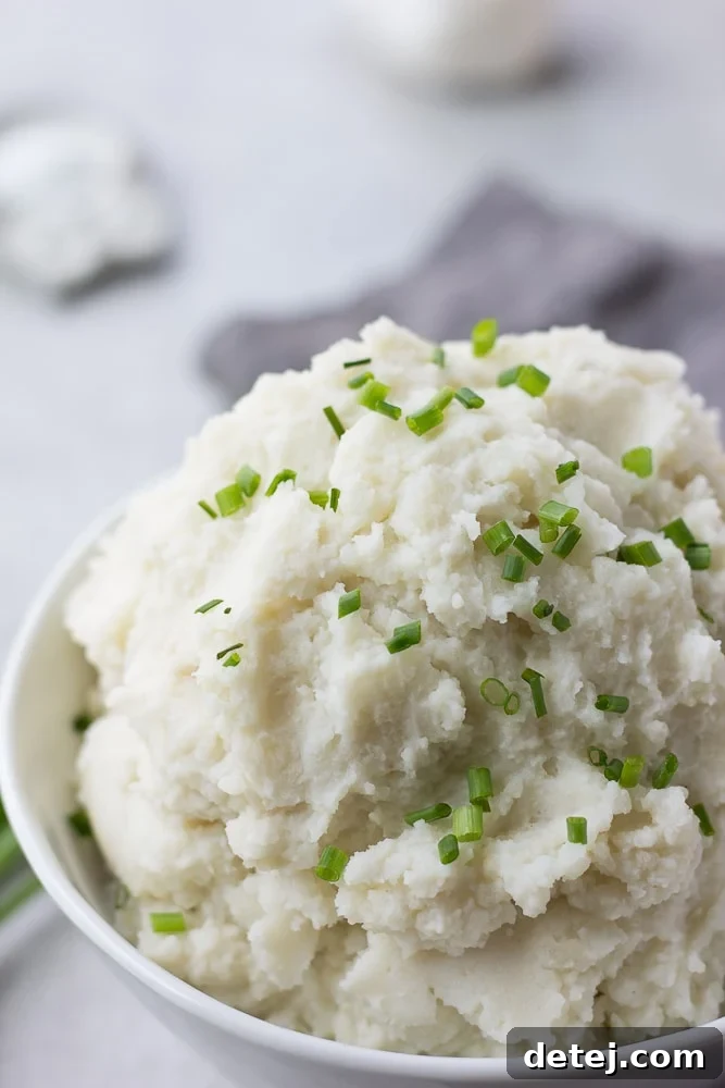 A close-up shot revealing the incredibly smooth and creamy texture of vegan mashed potatoes in a white bowl.
