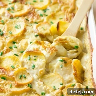 Creamy Vegan Potato Gratin 8 vegan scalloped potatoes in casserole dish with a wooden spoon