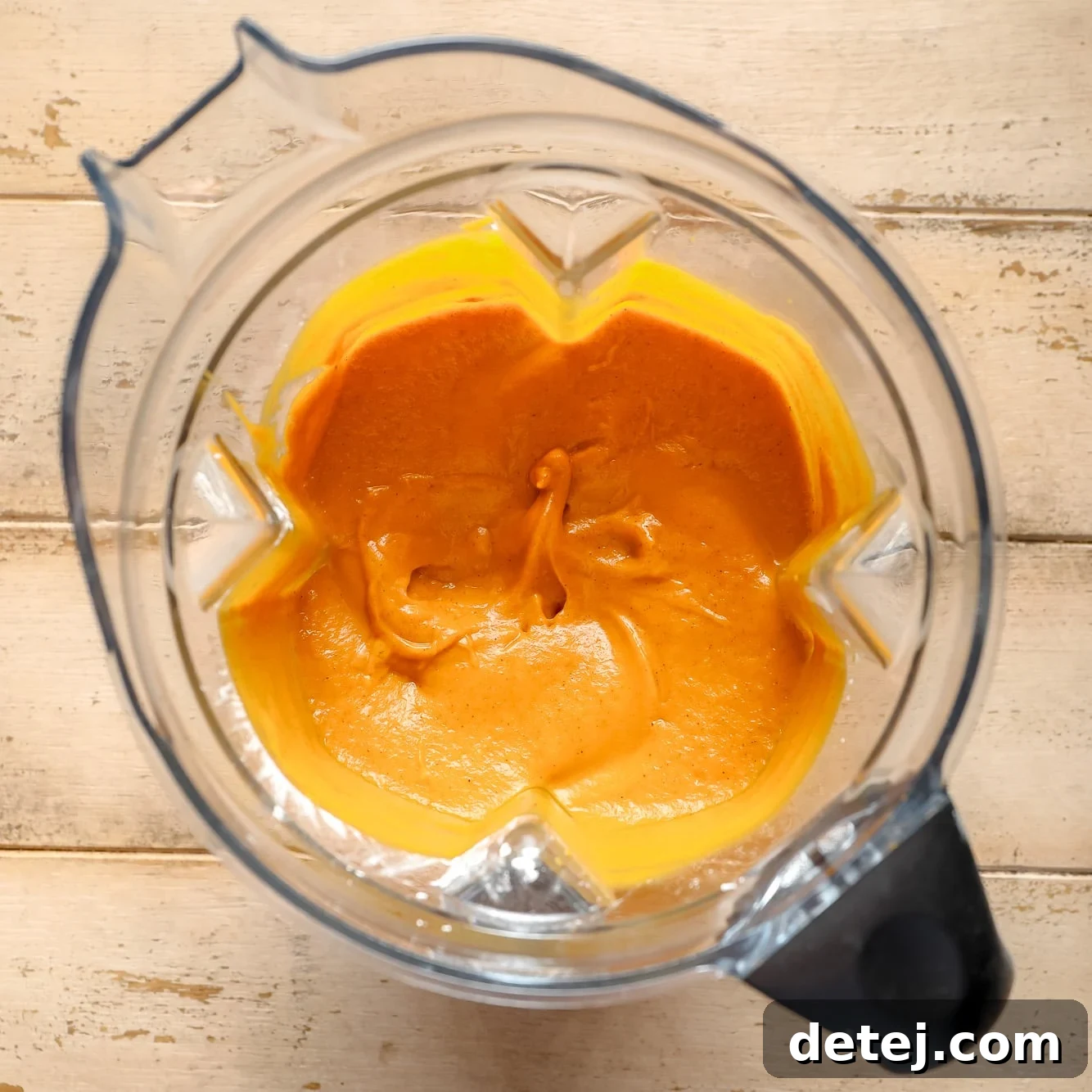 The smooth, vibrant orange pumpkin pie filling, perfectly blended and ready to be poured, is shown inside the blender.