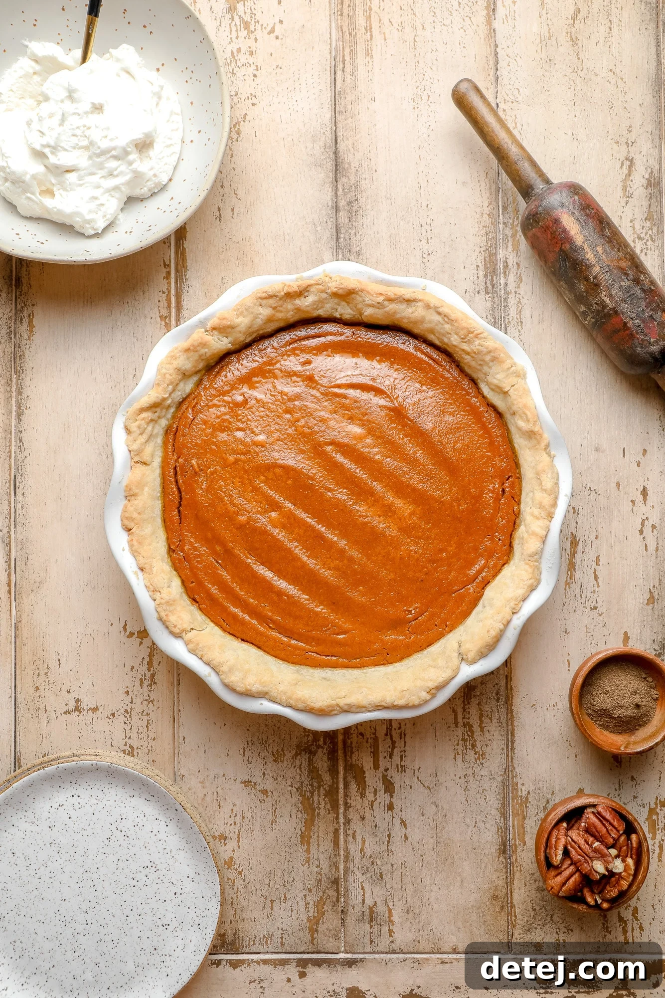 A freshly baked vegan pumpkin pie, golden brown and perfectly set in a white pie dish, just out of the oven and cooling.