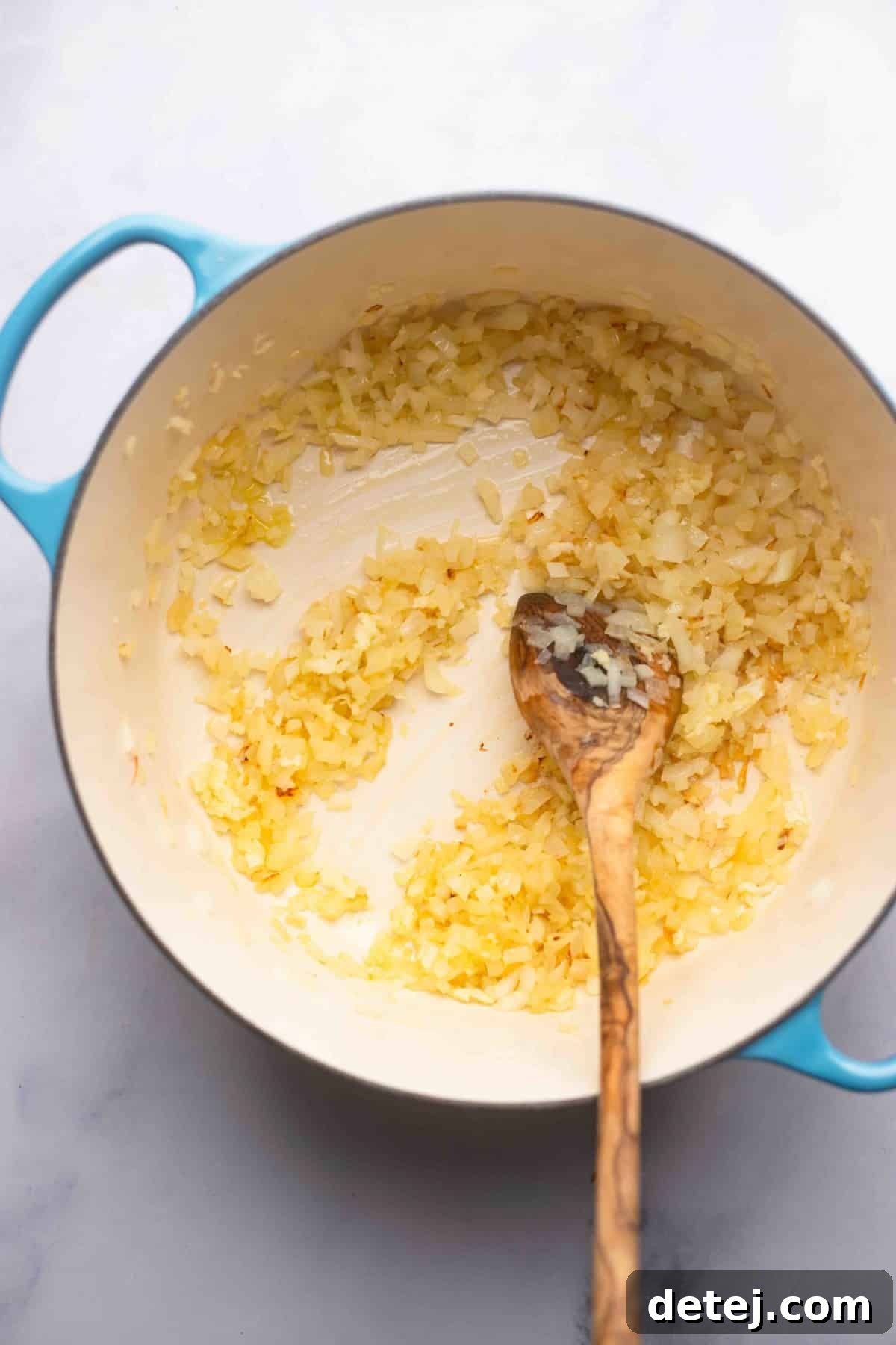 onions sauteed in a pan with wooden spoon