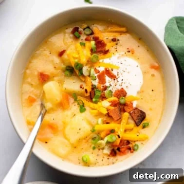 square image of a bowl of potato soup with lots of toppings like bacon, sour cream and cheese