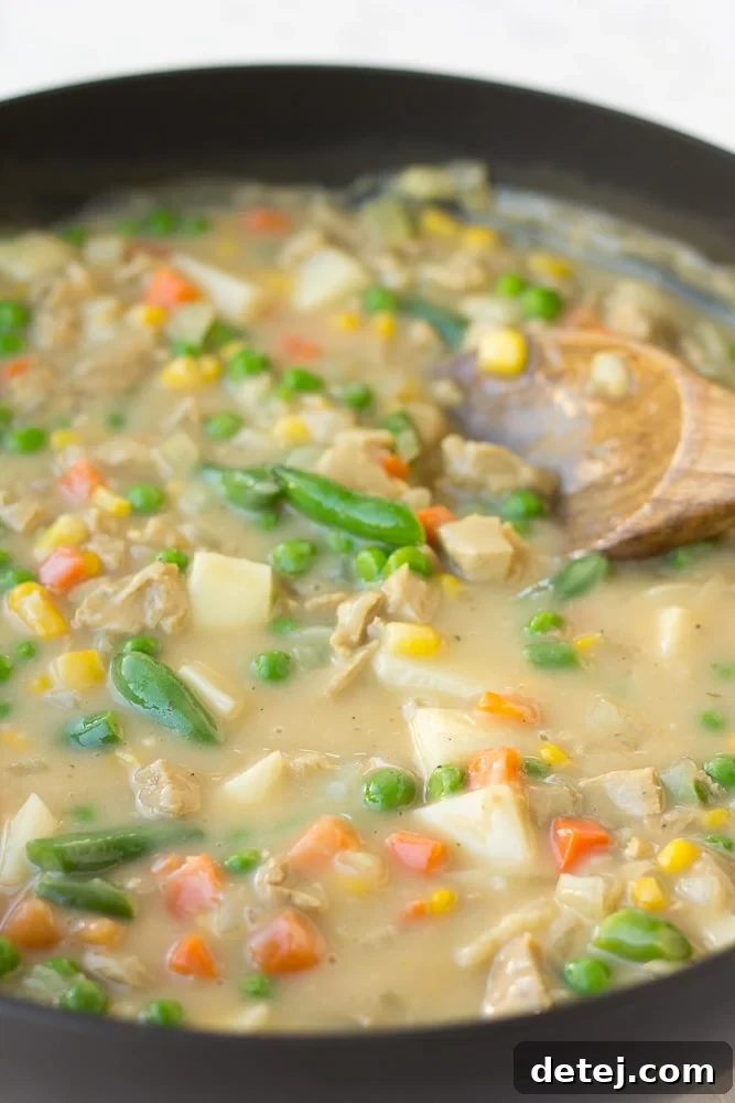 Rich and creamy filling for vegan pot pie simmering in a large skillet, featuring vibrant mixed vegetables and plant-based protein.