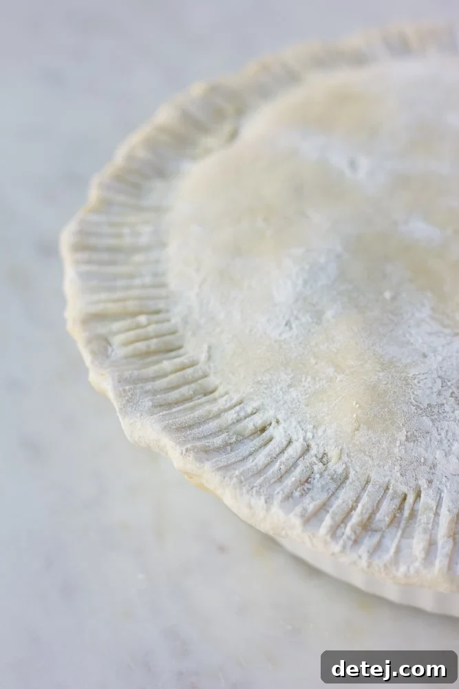 Unbaked vegan pot pie, ready for the oven, showcasing a beautifully crimped crust and steam vents.