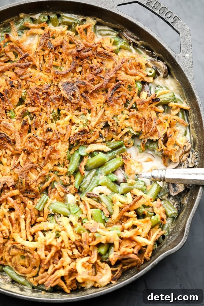 Looking down on a cast iron pan filled with creamy vegan green bean casserole and crispy fried onions, ready to serve.