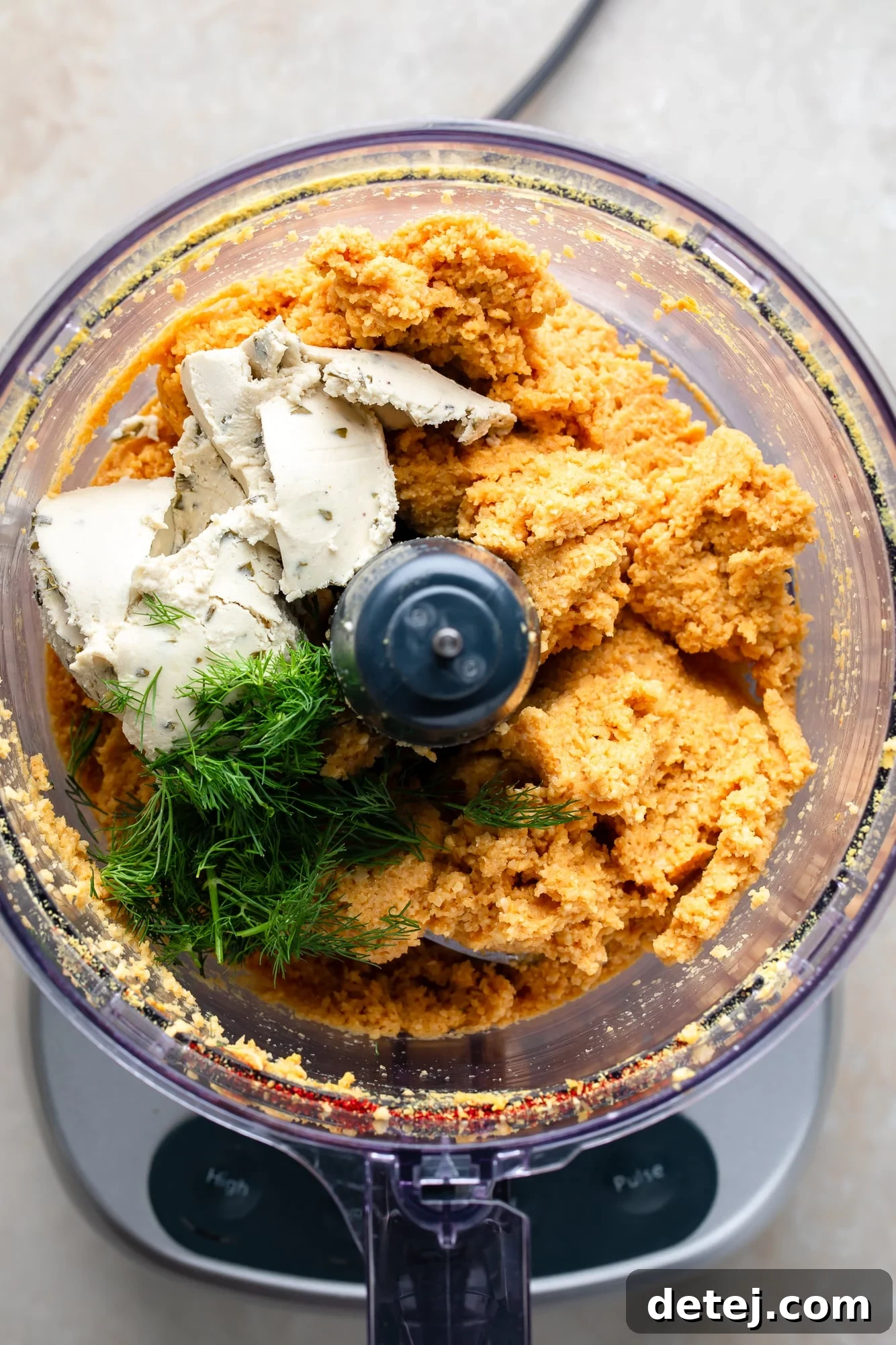 blending the ingredients for a vegan cheese ball in a food processor.