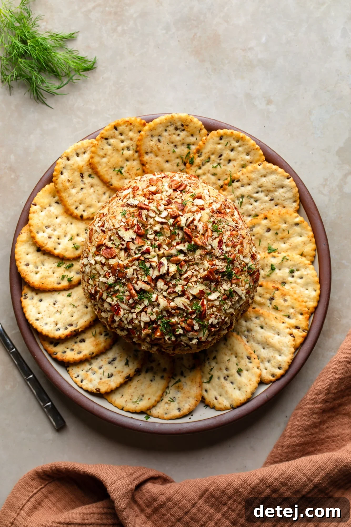 overhead view of a vegan cheese ball surrounded by crackers on a plate.