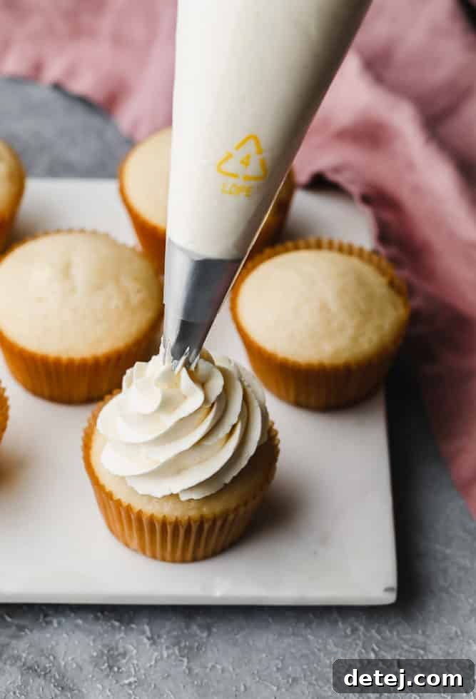 Dreamy Vegan Buttercream 11 A piping bag filled with vegan buttercream, completing the swirl on a cupcake, showcasing the beautiful finished product.