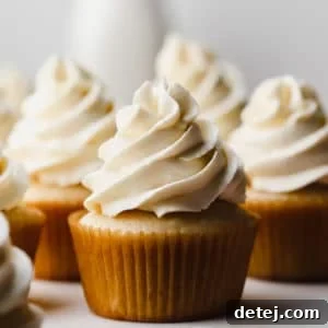 Square image of vanilla cupcakes with vegan frosting swirled on top