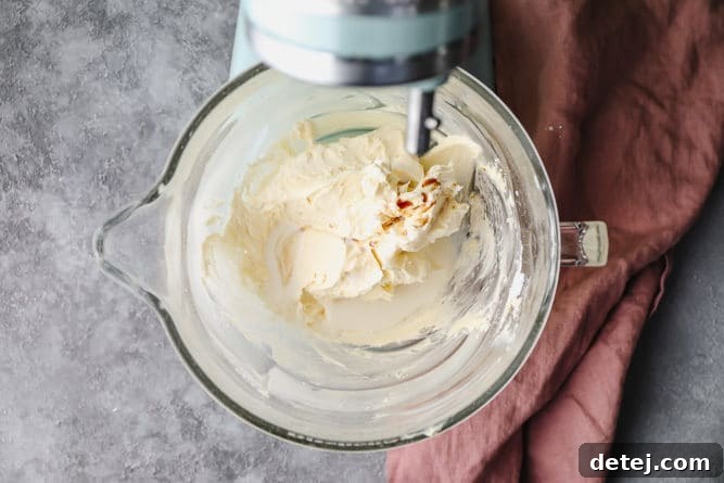 Dreamy Vegan Buttercream 6 Non-dairy milk and vanilla extract being added to the buttercream mixture in a stand mixer bowl.