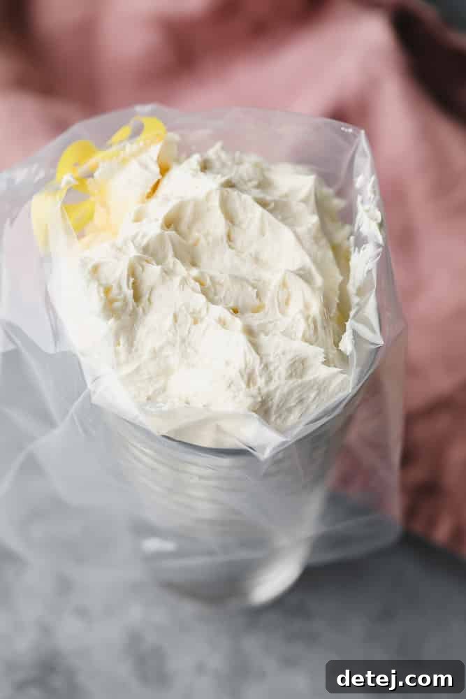 Dreamy Vegan Buttercream 8 A piping bag fitted with a tip, placed inside a tall glass with its edges folded over, filled with vegan buttercream frosting.