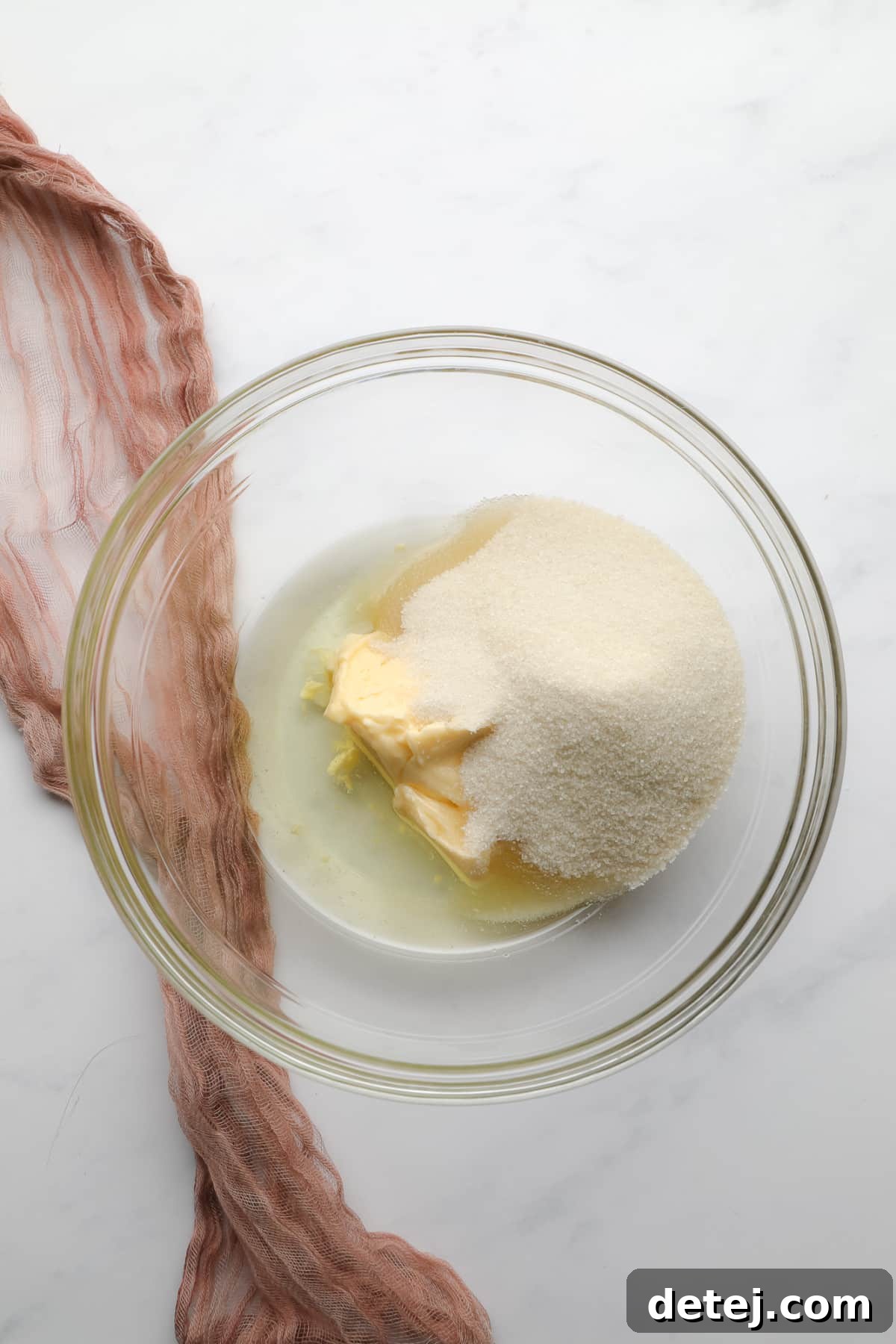 A glass mixing bowl containing vegan butter, canola oil, and sugar, before they have been creamed together.