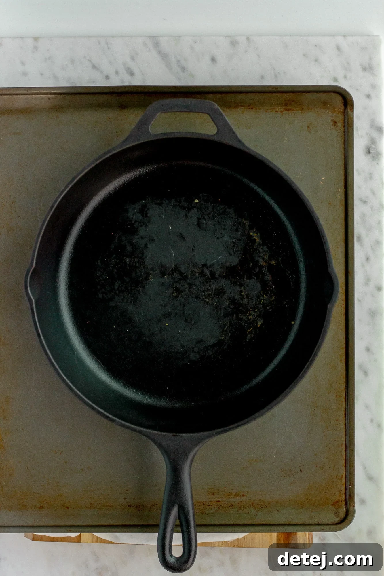 a black skillet placed on top of a baking sheet.
