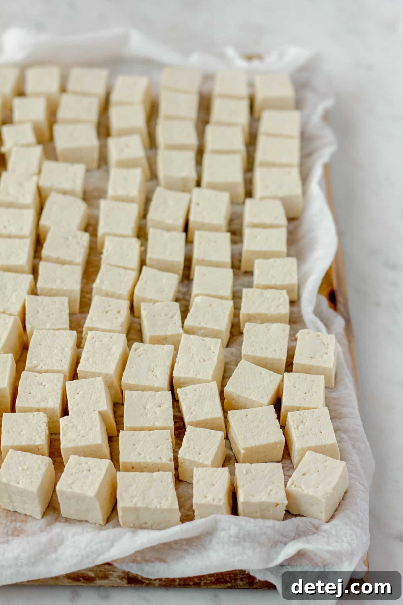 rows of tofu cubes on a paper towel-lined cutting board.