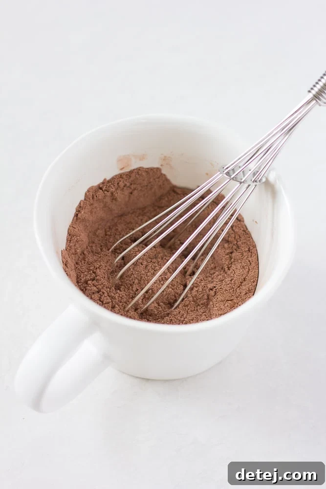 Dry ingredients being whisked in a mug for a vegan chocolate mug cake