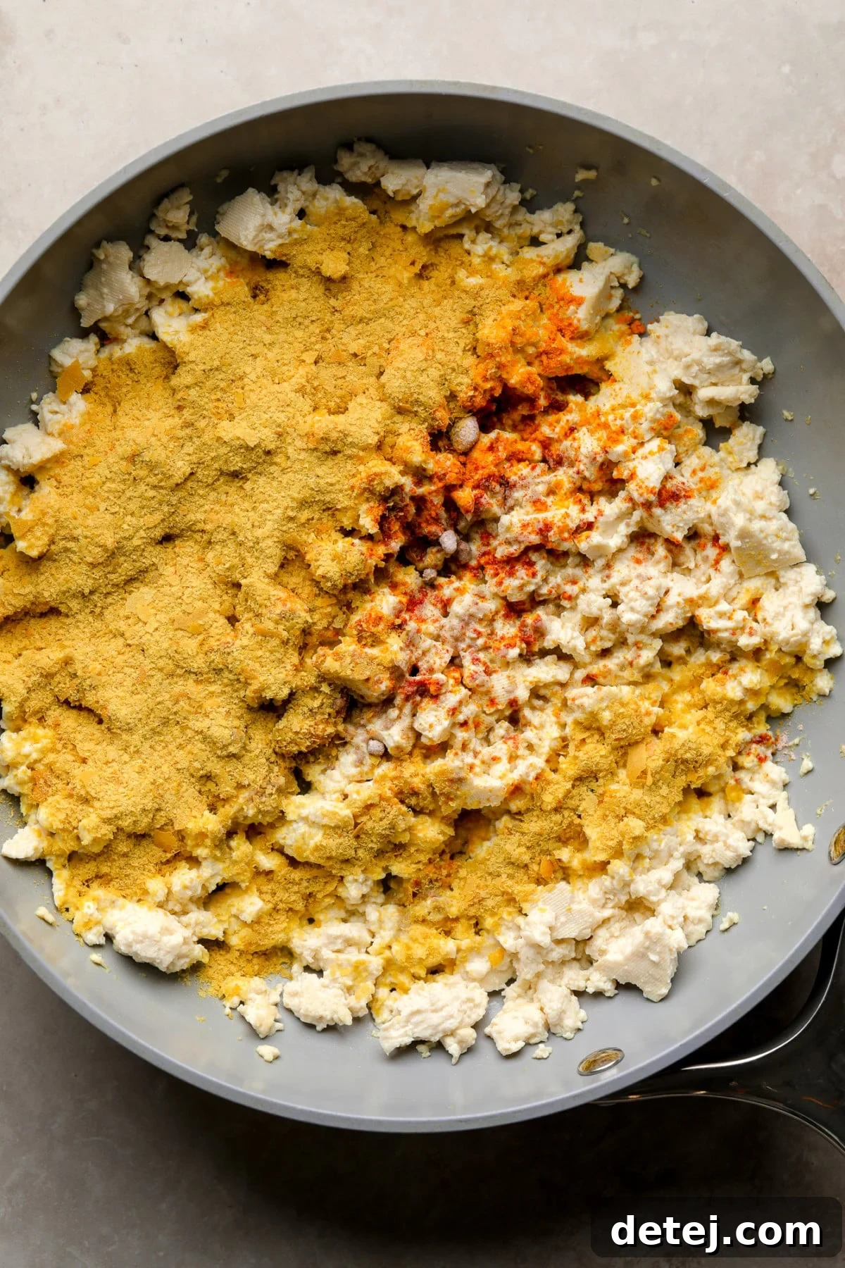 Crumbled tofu covered in yellow spices cooking in a skillet.