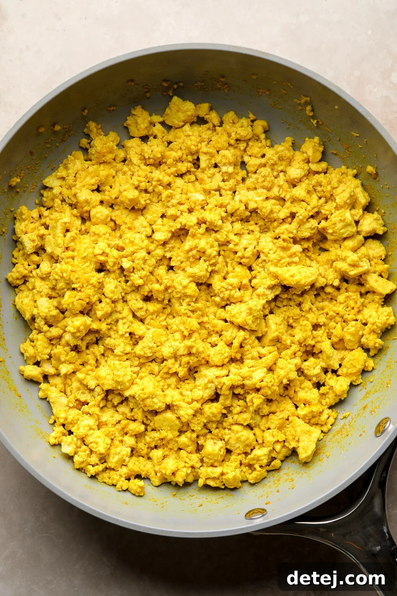 Golden yellow tofu scramble cooking in a skillet.