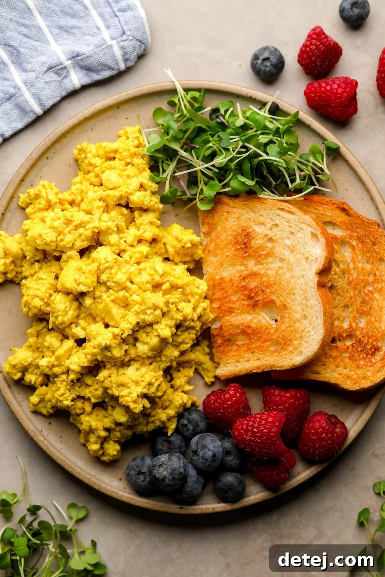 A beautifully plated yellow tofu scramble with toast, fresh greens, and berries, ready to be enjoyed.