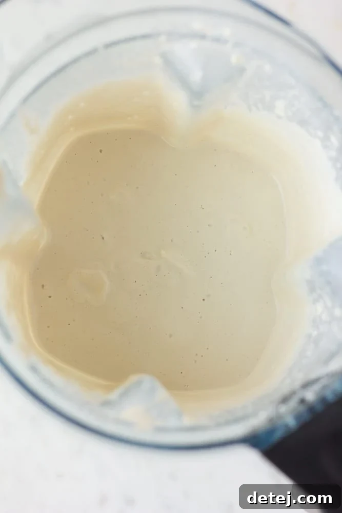 Luscious Vegan Green Goddess Dressing 5 Perfectly blended cashews in a blender, forming a smooth, creamy base for the green goddess dressing.