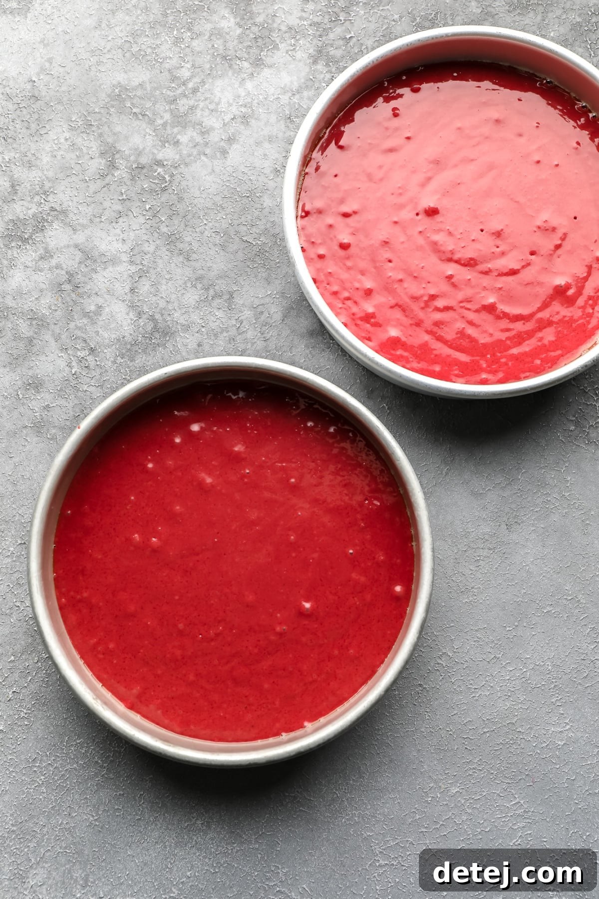 Ruby Red Vegan Indulgence 5 Vibrant red vegan cake batter evenly poured into two round cake pans, ready for baking.