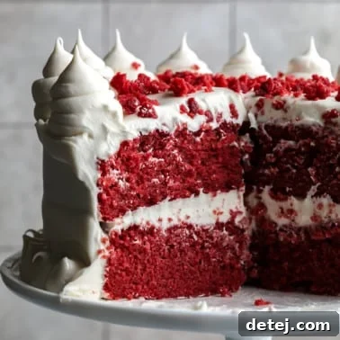 square image of a red cake with white frosting and red crumbles on top