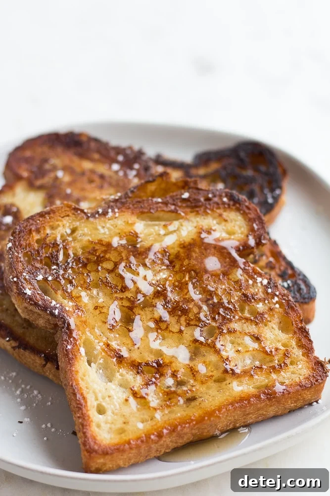 Delicious vegan French toast drizzled with maple syrup on a white plate, ready to be enjoyed.