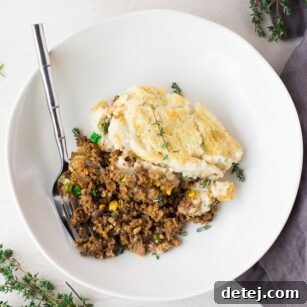 A bowl of vegan shepherd's pie, seen from above, with a fork poised to scoop.