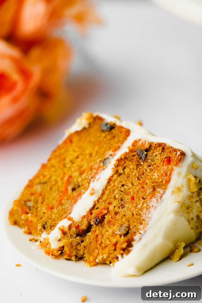piece of vegan carrot cake on a plate with orange flower in background