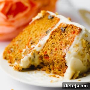 piece of orange cake on a plate with walnuts on the frosting
