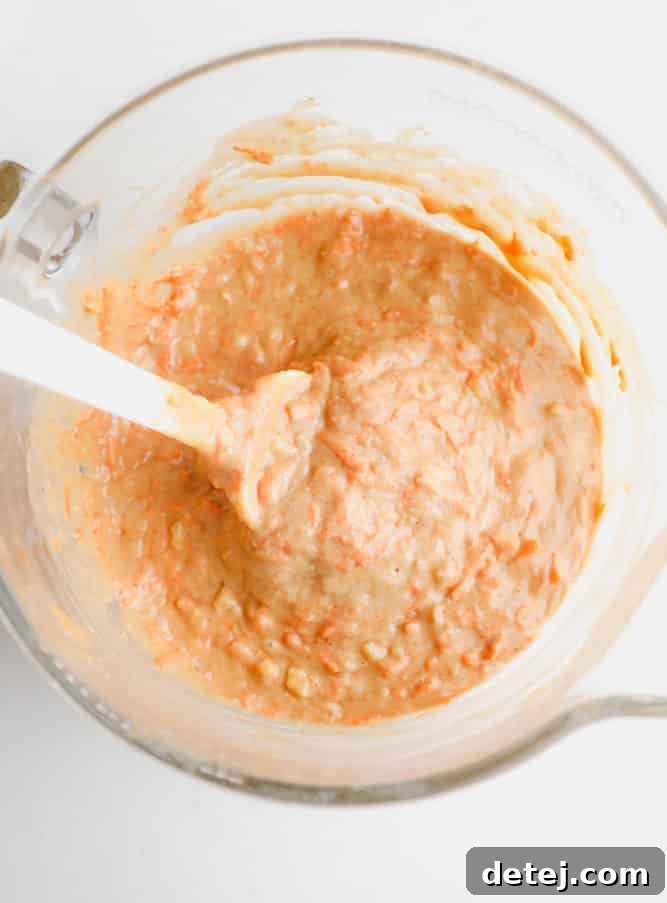 carrot cake batter in a clear bowl with a spatula