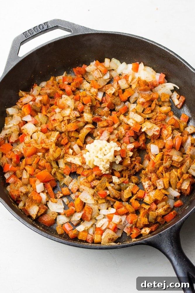 Sautéed red peppers and onions, perfectly softened and fragrant, simmering gently in a cast iron pan, ready for the next ingredients.