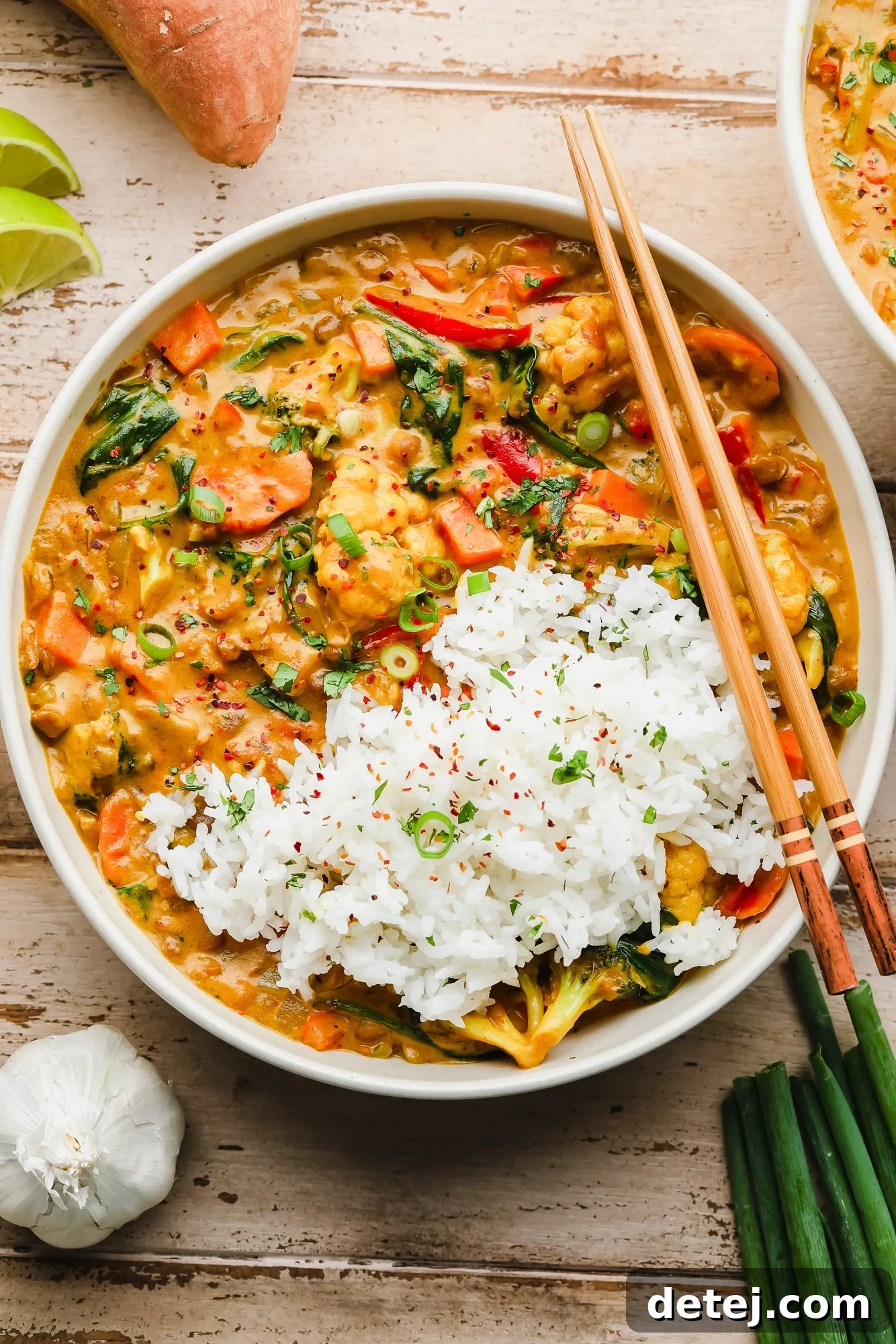 Quick and Flavorful Vegan Curry 2 A white bowl filled with creamy vegan curry and fluffy basmati rice, garnished with fresh cilantro. Wooden chopsticks rest on the side of the bowl.