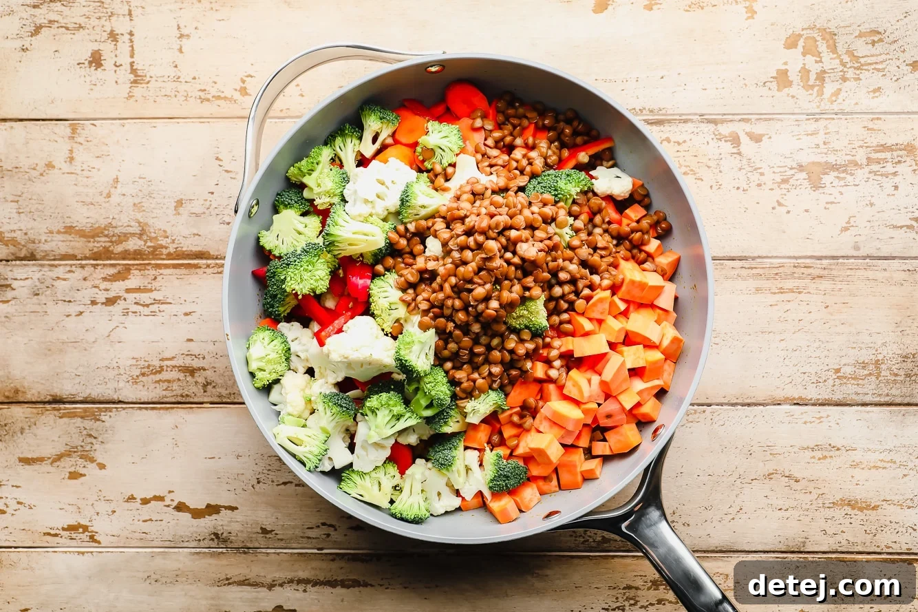 Quick and Flavorful Vegan Curry 5 A large grey pot filled with raw, chopped vegetables and drained lentils, ready to be simmered in the creamy coconut curry sauce.
