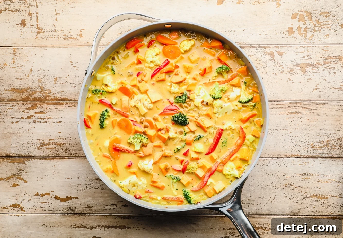 Quick and Flavorful Vegan Curry 6 A wide shot of a large grey pot filled with vibrant, cooked yellow vegan curry, bubbling gently on the stovetop.