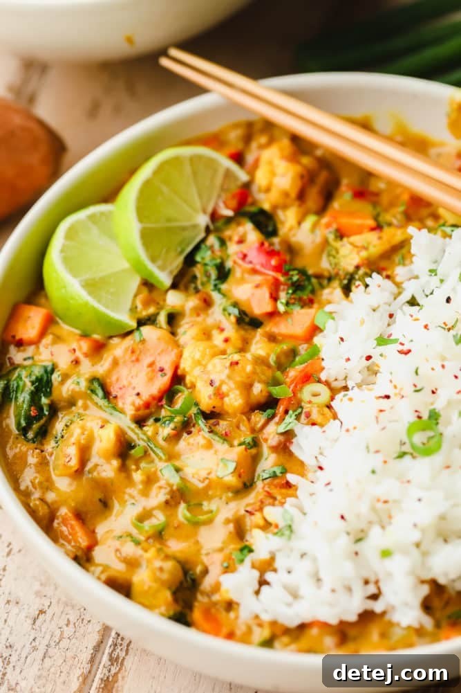 Quick and Flavorful Vegan Curry 8 A close-up shot of a white bowl overflowing with a rich vegan curry, served alongside fluffy white rice, adorned with lime wedges and cilantro. Wooden chopsticks are poised for enjoyment.