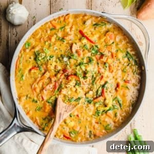 Quick and Flavorful Vegan Curry 9 A large grey pot filled with cooked vegan curry, with a wooden spoon sticking out, ready to be served.