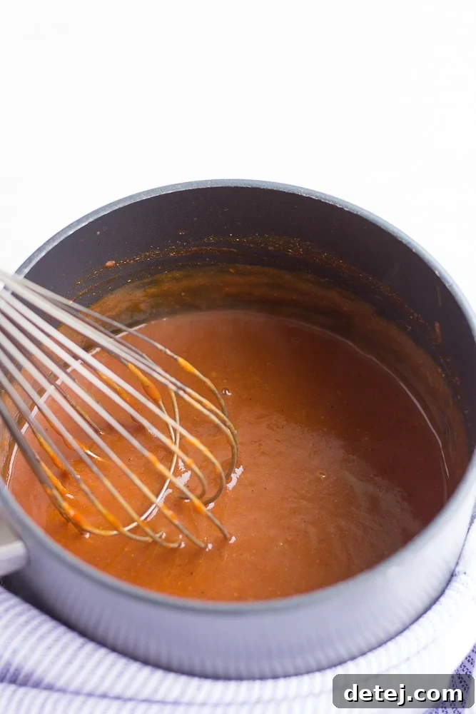 Ultimate Vegan Enchiladas 5 A small saucepan containing vibrant red enchilada sauce, with a whisk resting inside, ready for the next step.
