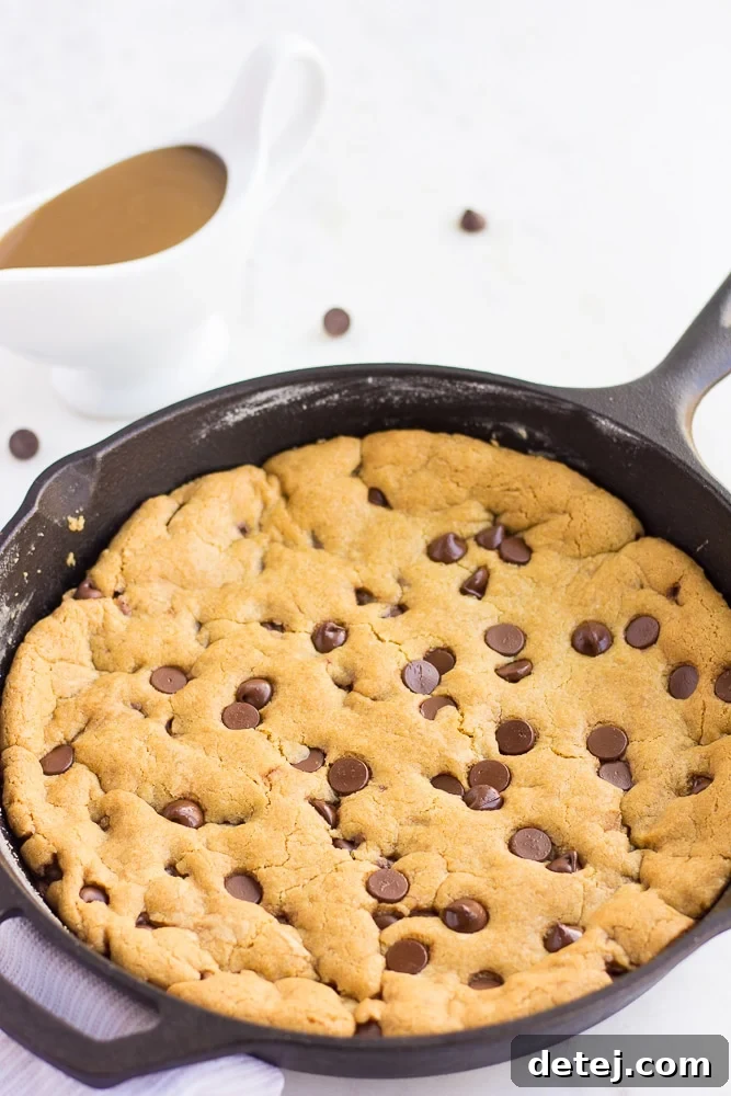 Freshly baked vegan skillet cookie, golden brown around the edges and still warm and gooey in the center, straight out of the oven.