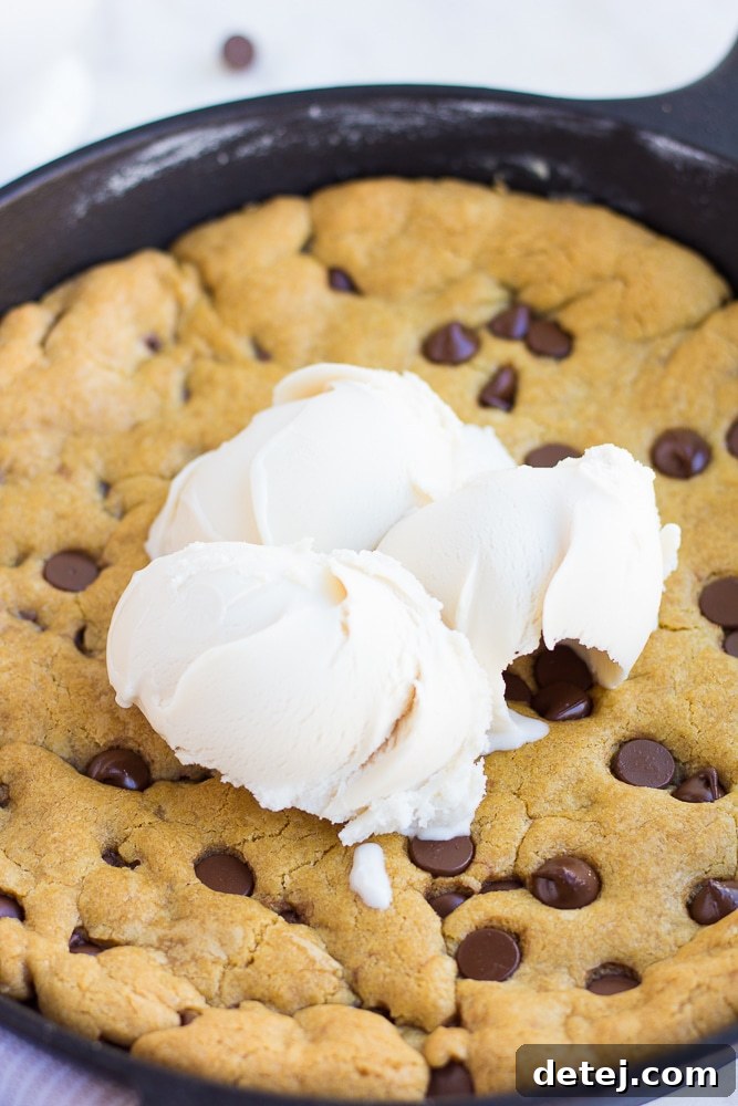 Warm vegan skillet cookie topped with generous scoops of non-dairy vanilla ice cream, ready for serving.