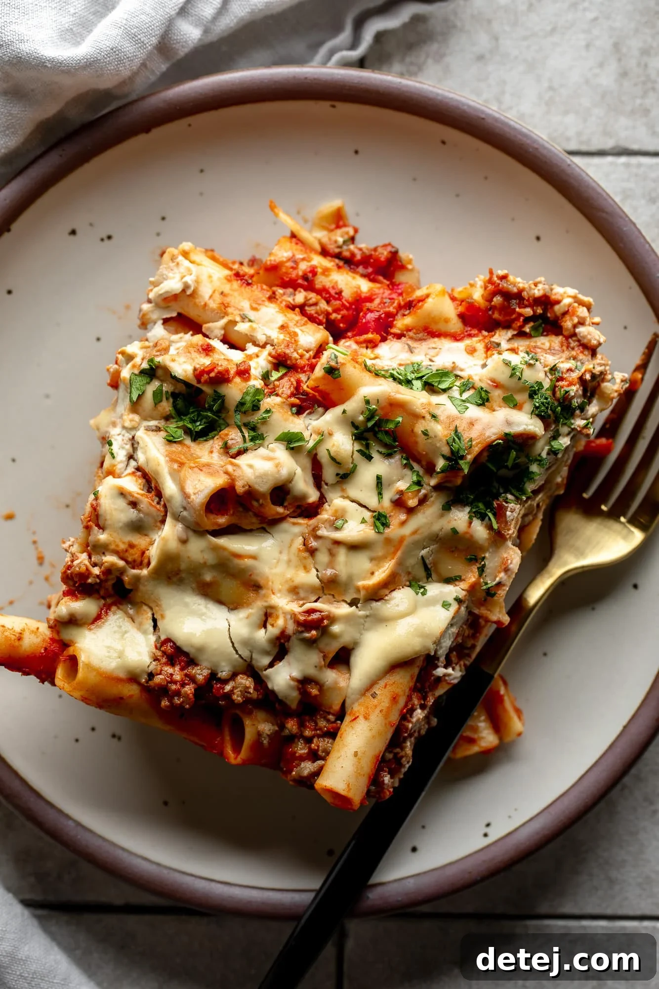 A scoop of Vegan Baked Ziti served on a pristine white plate, garnished with fresh herbs, ready to be enjoyed.