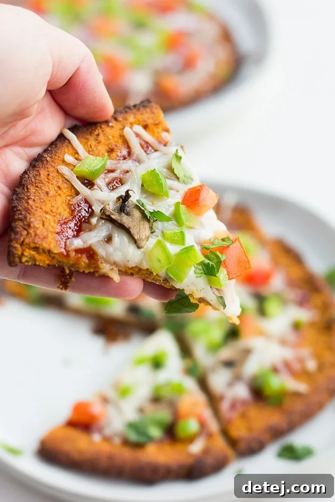 hand holding sweet potato pizza crust with toppings, cooked.