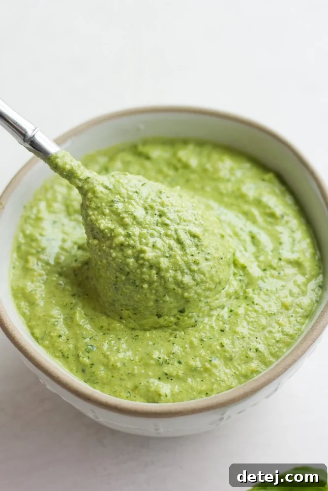 spoonful being taken out of a bowl with pesto in it, white background.