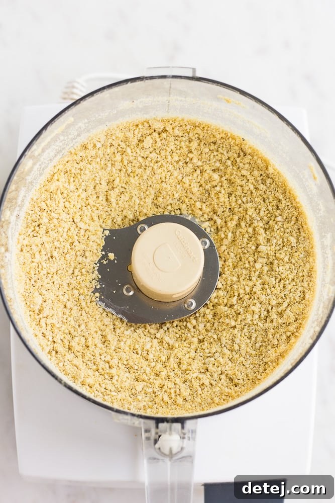 Finely processed cashew vegan parmesan in a food processor, displaying its ideal crumbly texture.