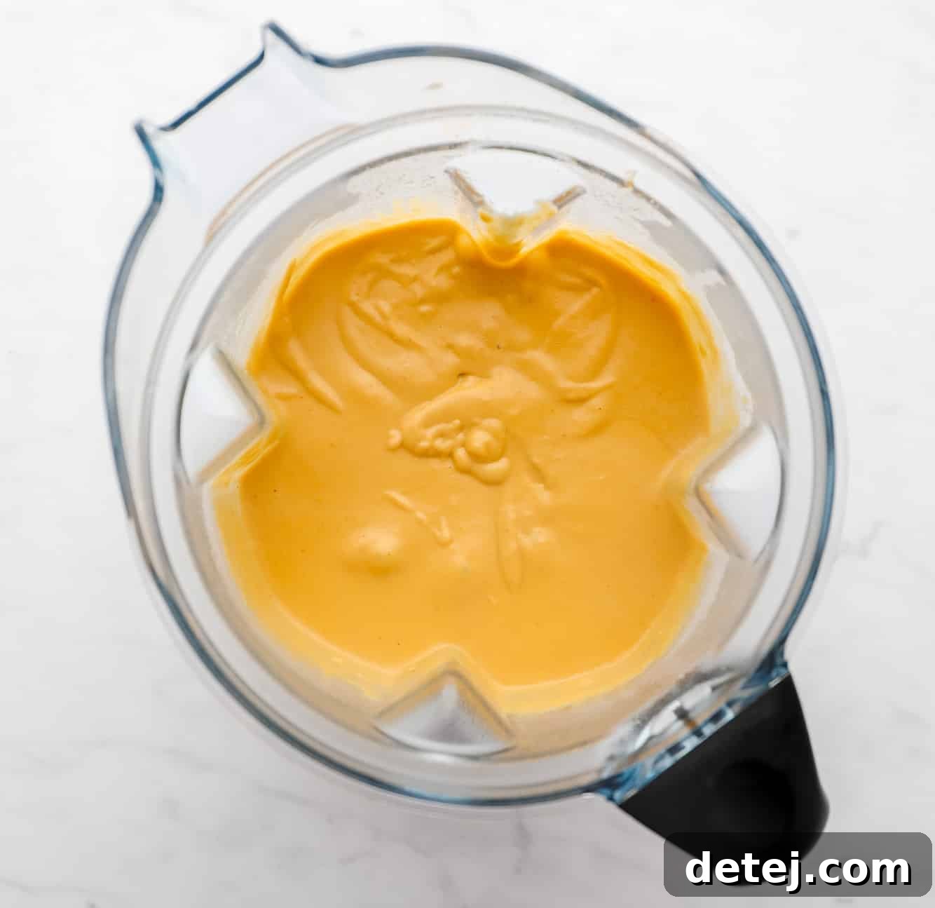 A creamy, yellow, blended mixture in a large blender.
