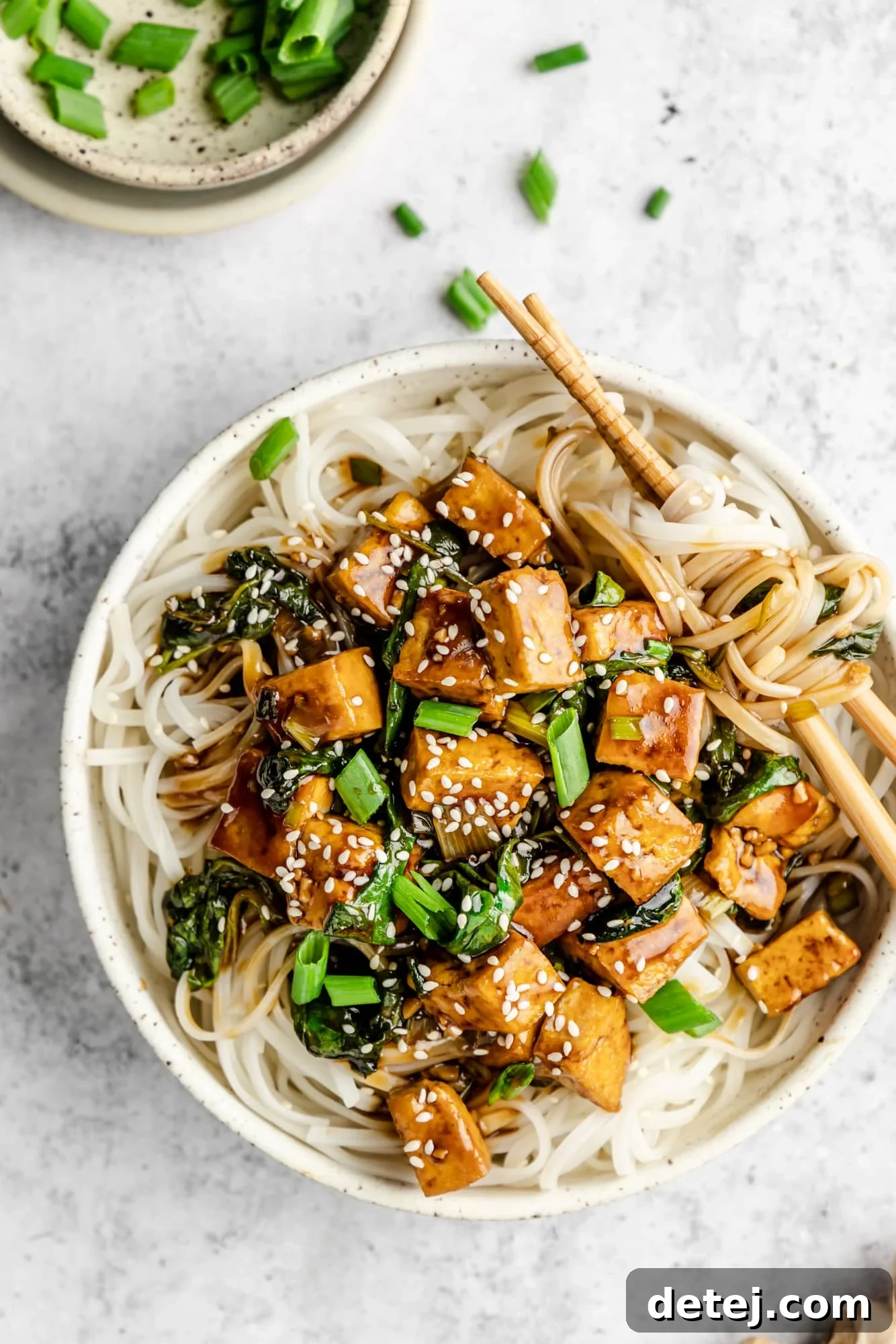Effortless One Pan Tofu Stir Fry 8 tofu stir fry served over rice noodles in a white bowl.