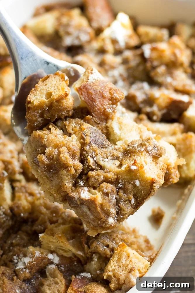 Ultimate Vegan French Toast Bake 3 A spatula carefully lifting a perfect square of golden-brown vegan French toast casserole from a baking dish, showcasing its fluffy texture.